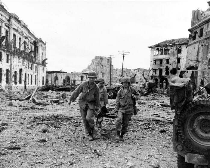 Liberation of Manila, 1945. Stretcher party brings out a wounded U.S. soldier, following an attack by U.S. troops to liberate Filipino prisoners in the walled city, 23 February 1945. Note wrecked buildings.