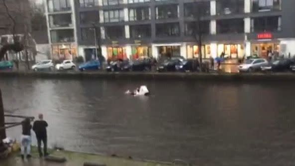 As the car sinks into the canal, the rescuers can be seen desperately trying to free the trapped woman and her baby. Photo: RTL Nieuws