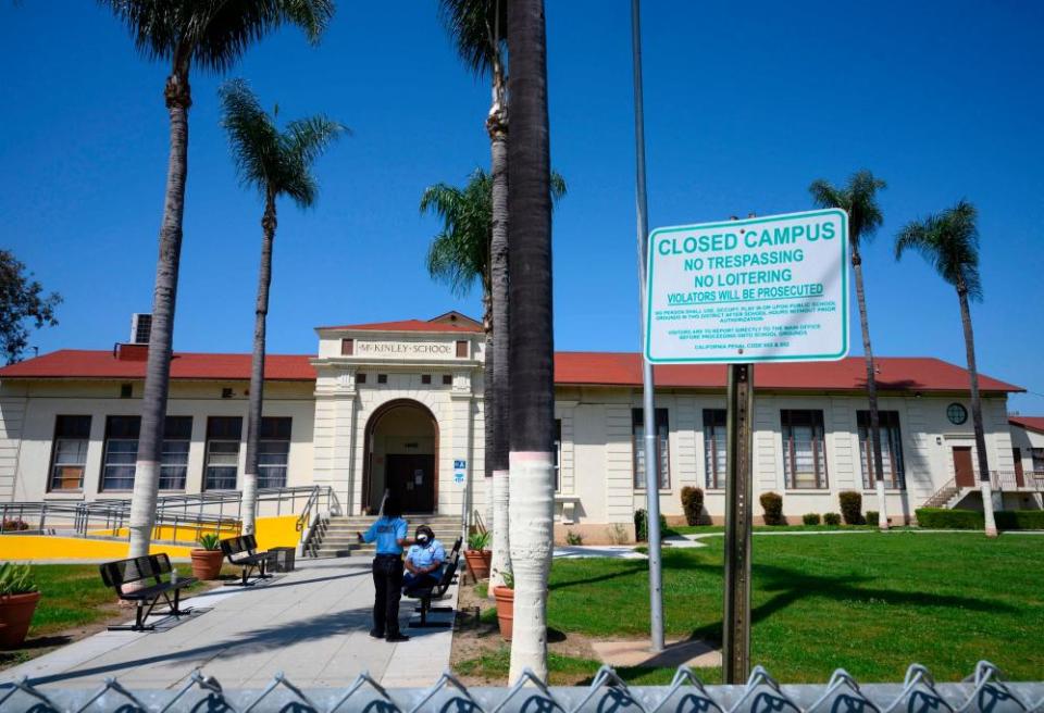 Security guards talk on the campus of the closed McKinley School, part of the Los Angeles Unified School District (LAUSD) system, in Compton, California, just south of Los Angeles.