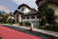 A cleaner stands in front of a house for sale at the replica village of Austria's UNESCO heritage site, Hallstatt, in China's southern city of Huizhou in Guangdong province, June 1, 2012.