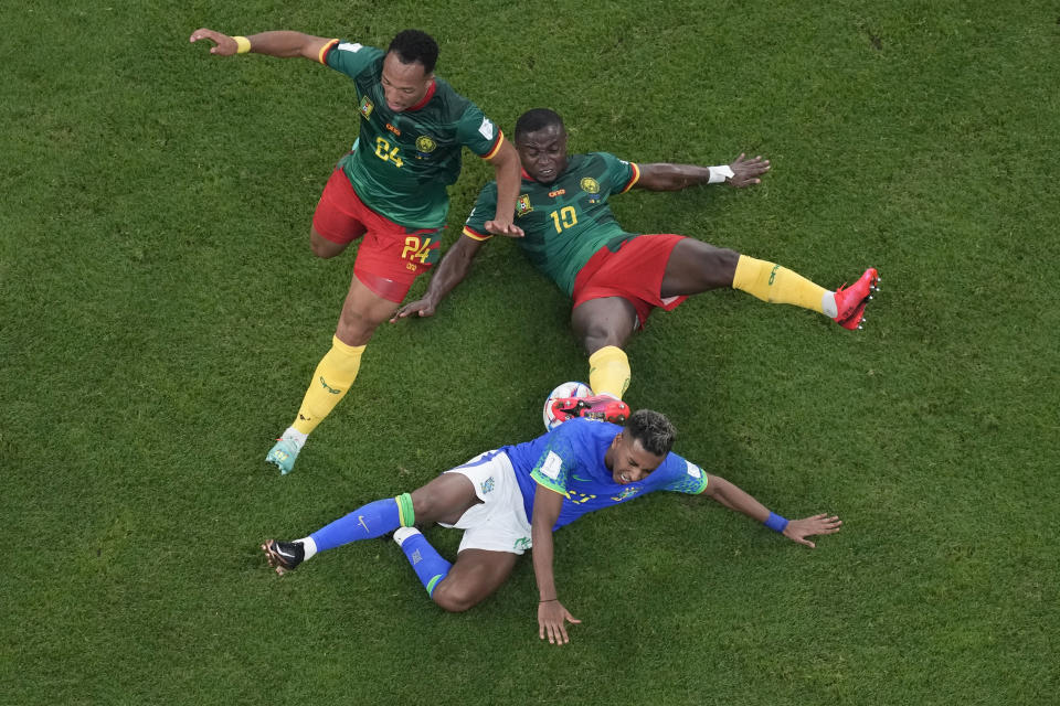 Brazil's Rodrygo falls to the ground in a clash with Cameroon's Enzo Ebosse, left, and Collins Fai during the World Cup group G soccer match between Cameroon and Brazil, at the Lusail Stadium in Lusail, Qatar, Friday, Dec. 2, 2022. (AP Photo/Thanassis Stavrakis)