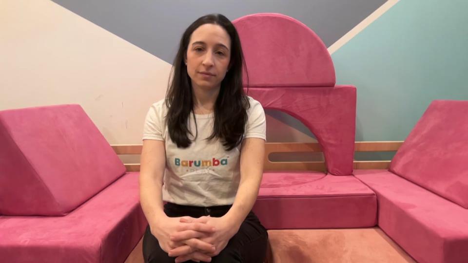 Sara Feldstein sits on a Barumba Play couch, covered in pink slip covers that are examples of what Canada Border Services Agency says she must pay tens of thousands of dollars in tariffs for.