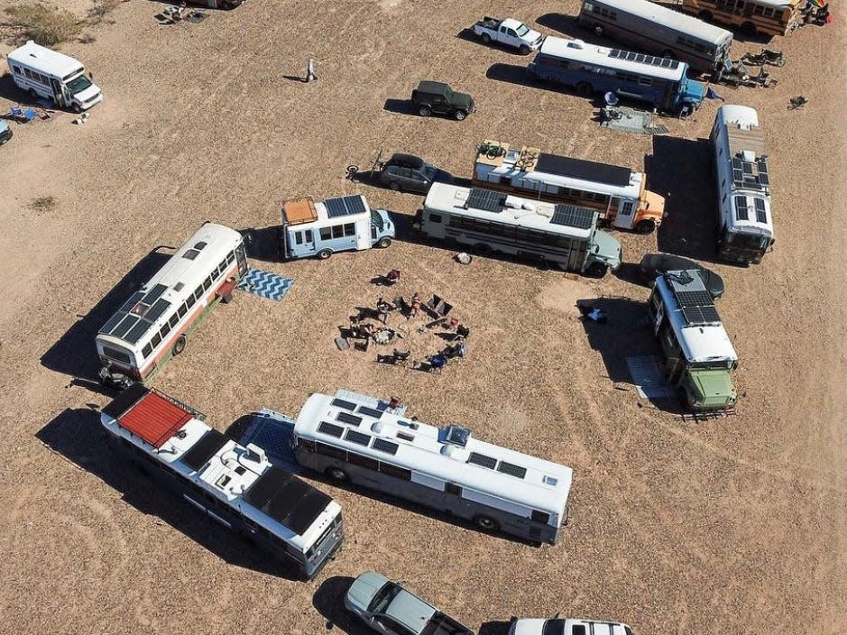 Several buses and RVs parked around each other on dirt road