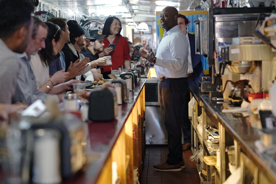 Sen. Tim Scott, R-S.C., talks with diners and reporters during a visit to the Red Arrow Diner, Thursday, April 13, 2023, in Manchester, N.H. Scott on Wednesday launched an exploratory committee for a 2024 GOP presidential bid, a step that comes just shy of making his campaign official. (AP Photo/Charles Krupa)