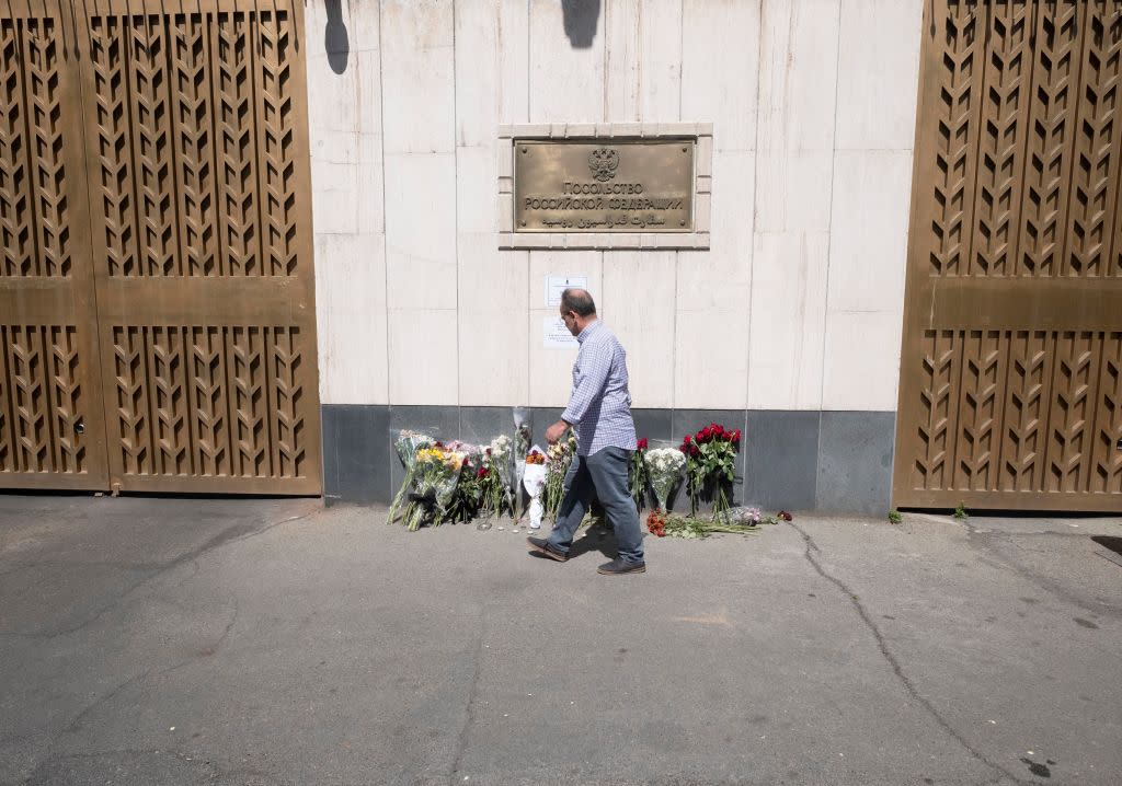  A man walks past flowers placed outside the Russian embassy in Tehran, Iran, to honor the victims of a shooting at the Crocus City Hall concert venue near Moscow, Russia. 