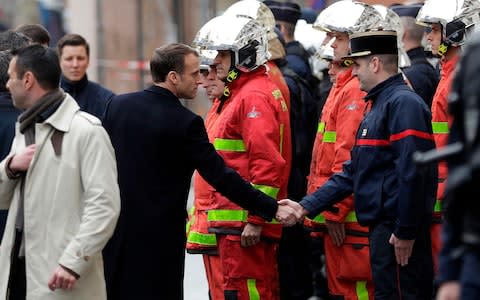 French President Emmanuel Macron (L) shakes hands with a firefighter during a visit in the streets of Paris on December 2, 2018, a day after clashes during a protest of Yellow vests (Gilets jaunes) against rising oil prices and living costs.  - Credit:  GEOFFROY VAN DER HASSELT/ AFP