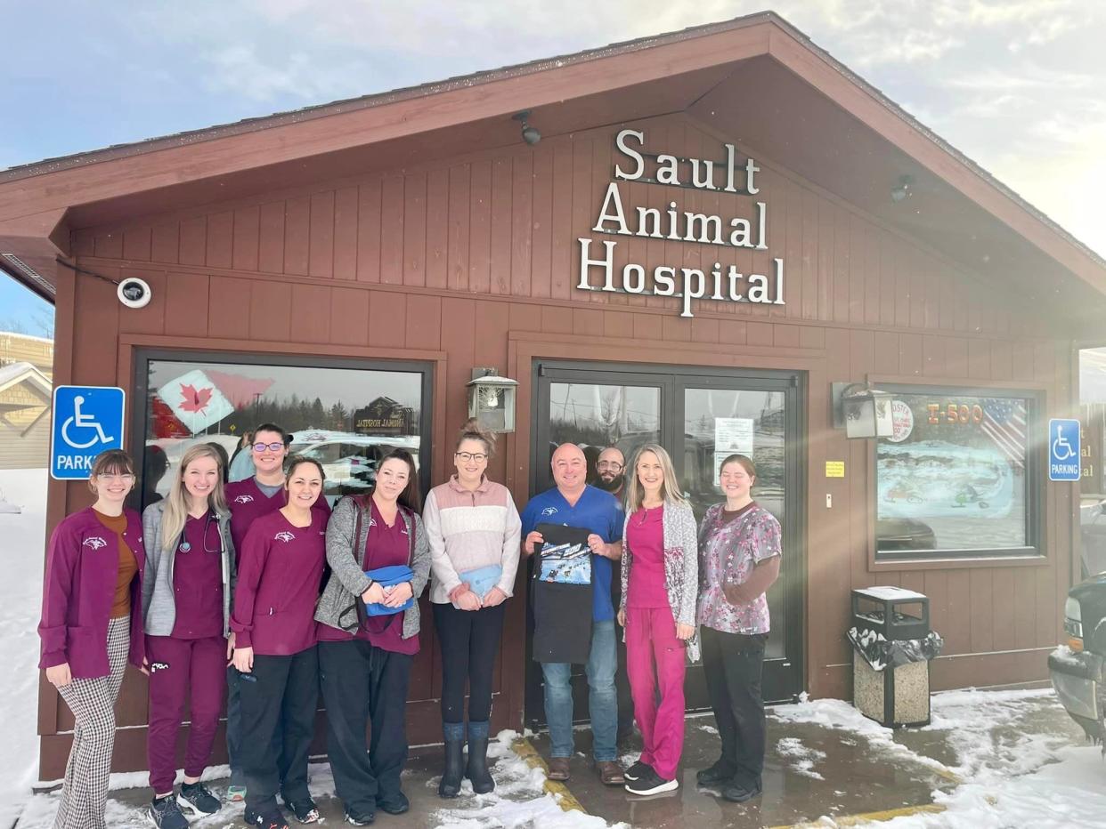 The staff of the Sault Animal Hospital stand in front of their contest winning window decoration for the I-500 business decorating contest.