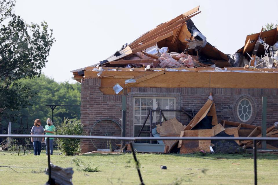 People walk around a house with storm damage in Oklahoma City. A possible tornado came through the area near Cimarron Road and NW 10 on Sunday evening.