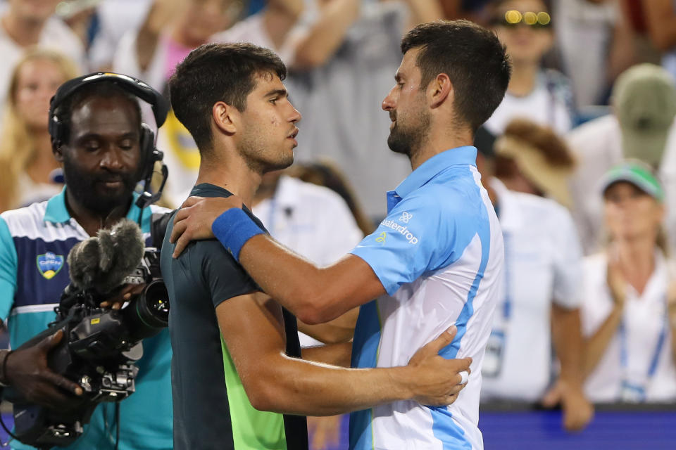 Carlos Alcaraz and Novak Djokovic embrace.