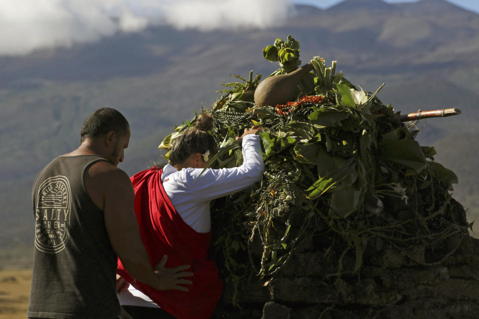 FILE - In this Sunday, July 14, 2019, file photo, Native Hawaiian activists pray at the base of Hawaii's Mauna Kea, background. For activists who say they're protecting Mauna Kea, the fight against the proposed Thirty Meter Telescope is a boiling point in Hawaiian history: the overthrow on the Hawaiian kingdom, battles over land, water and development and questions about how the islands should be governed. (AP Photo/Caleb Jones, File)