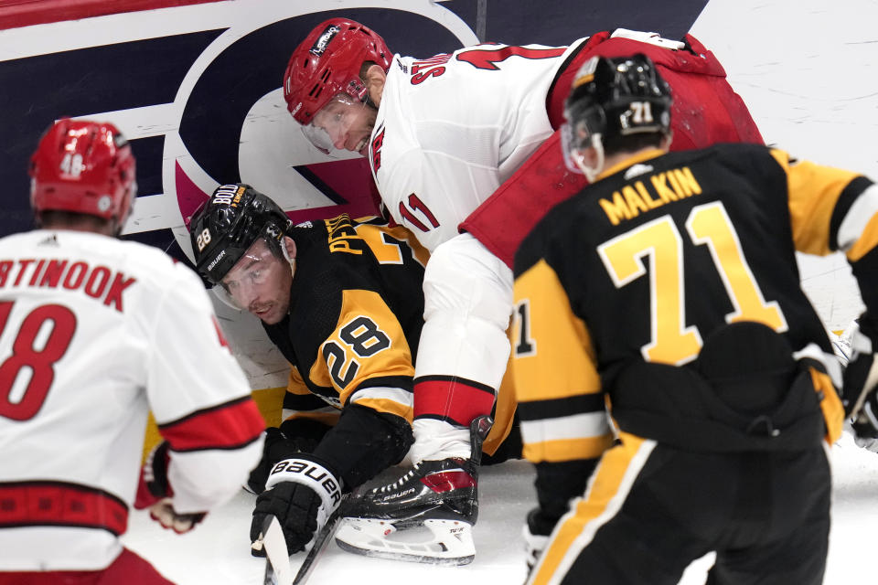 Pittsburgh Penguins' Marcus Pettersson (28) is checked to the ice by Carolina Hurricanes' Jordan Staal (11) during the first period of an NHL hockey game in Pittsburgh, Tuesday, March 26, 2024. (AP Photo/Gene J. Puskar)