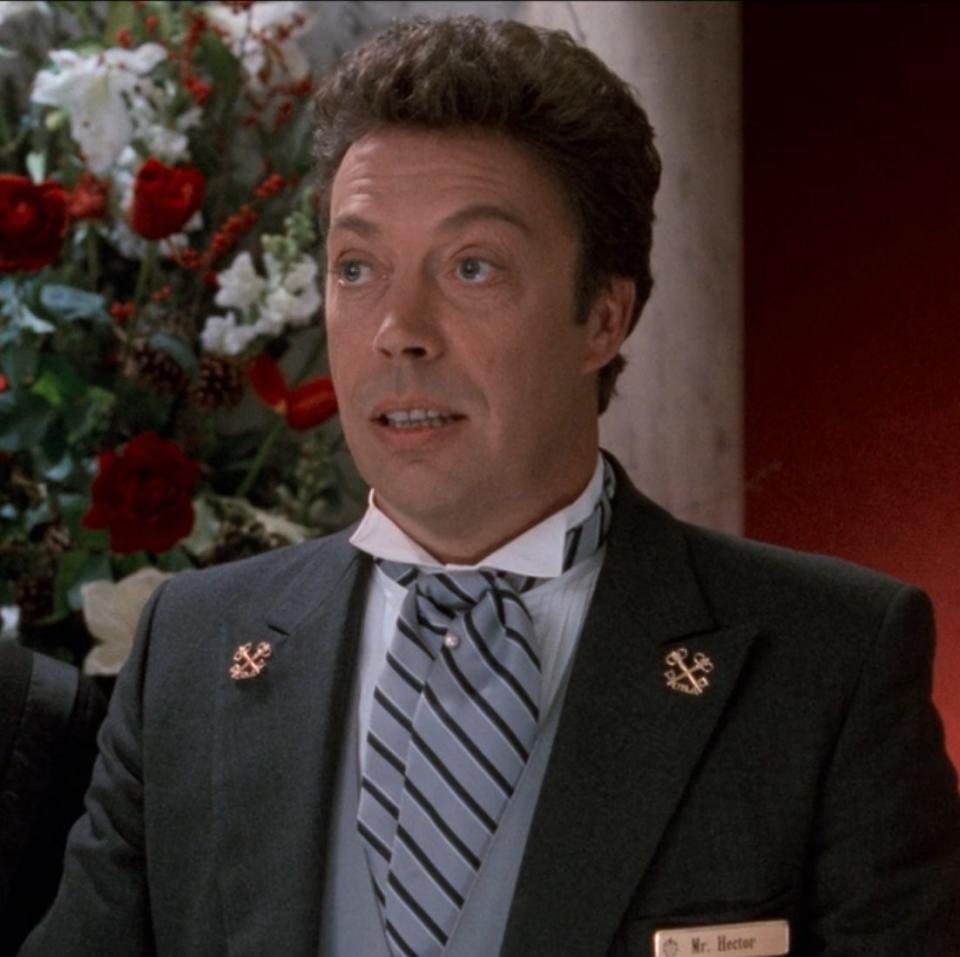 Tim Curry as Mr. Hector speaks to Kevin's parents at the Plaza Hotel front desk