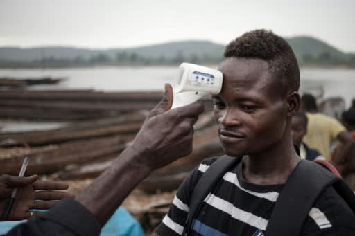 A health worker in the Central African Republic monitors the temperature of a young traveller from DRCongo