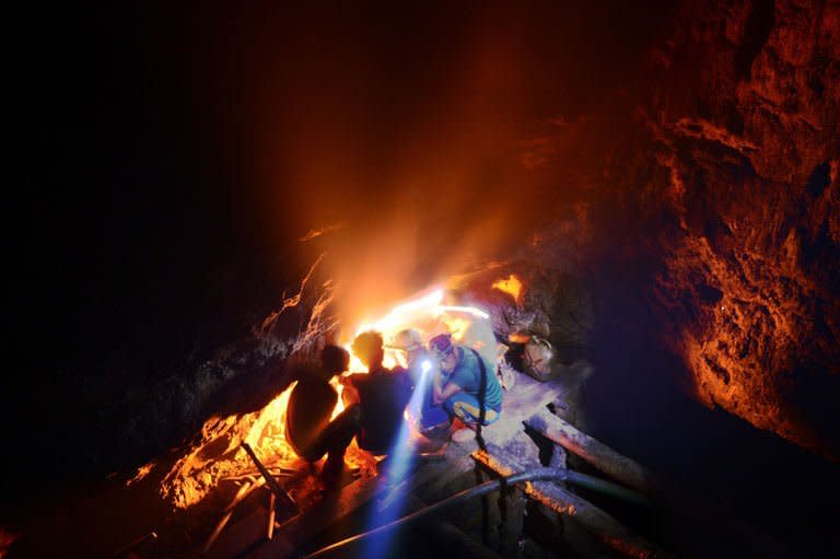 Indian child coal miners squat by a fire to keep warm inside a 50 metre-deep shaft in Rymbai village in the northeastern state of Meghalaya on January 29, 2013. Child labour is officially illegal in India, but in Meghalaya thousands of children work in rat-hole mines too small for adults to enter