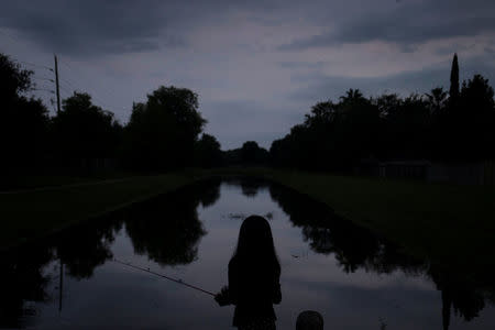 Mitchelle Sanchez, 8, fishes in a bayou in the aftermath of Tropical Storm Harvey in Houston, Texas, U.S. September 4, 2017. REUTERS/Adrees Latif
