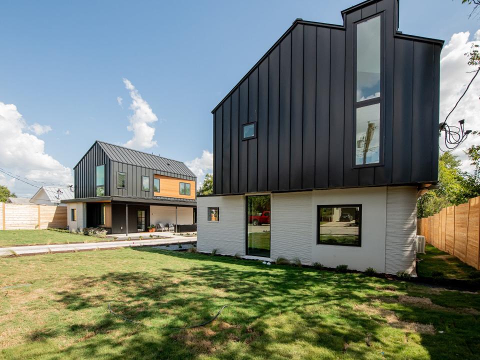 a row of 3D printed homes on a patch of grass