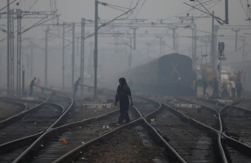 A woman crosses a railway line on a smoggy morning in New Delhi