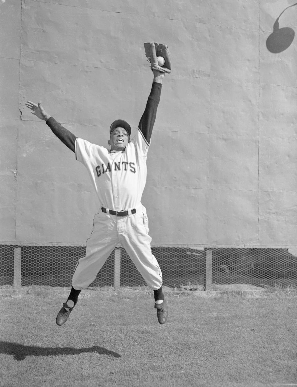 Willie Mays in a Giants uniform making a leaping catch