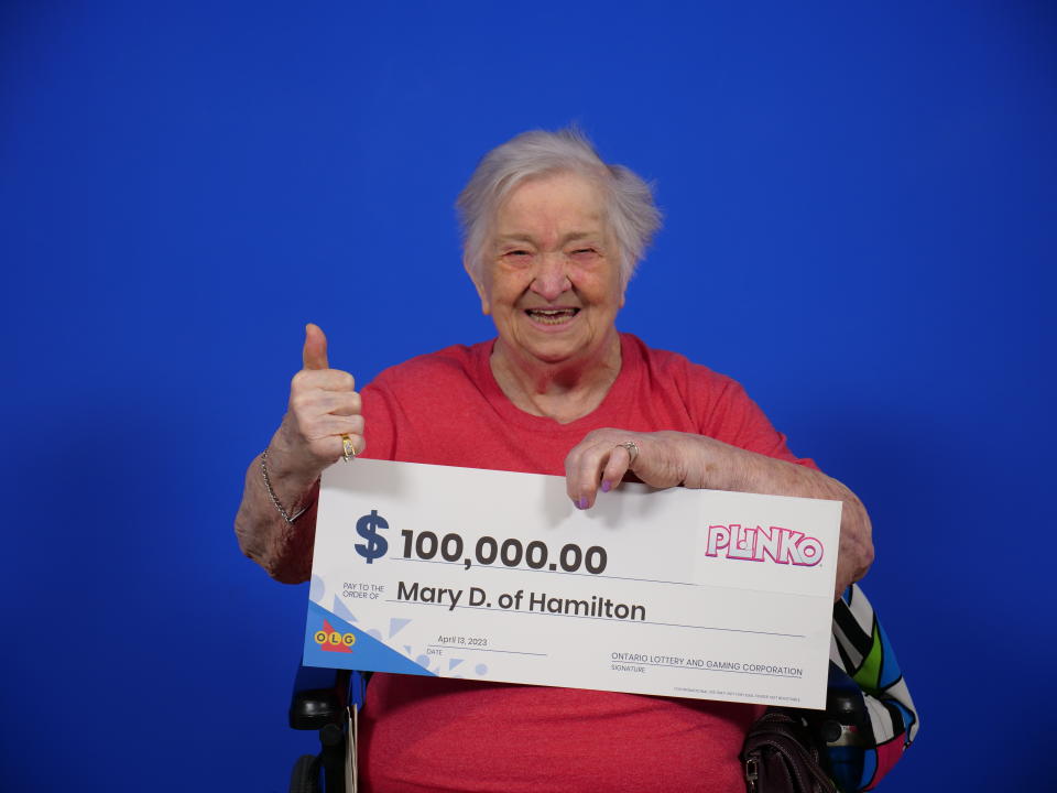 Mary Divok sitting in a wheelchair and holding a cheque worth $100,000