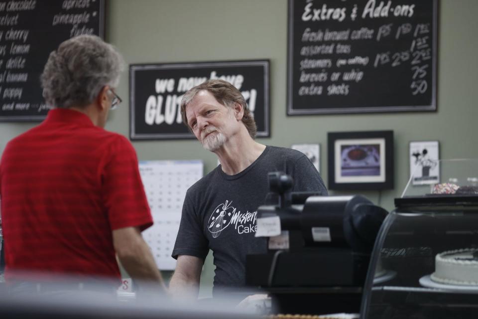 A man behind a counter waits on a customer.