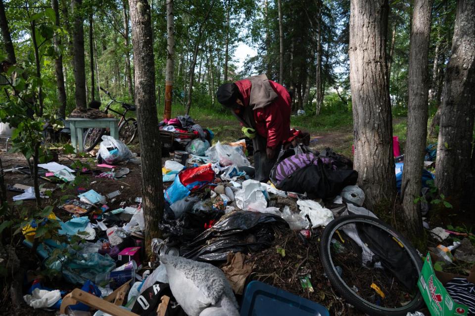 A volunteer helps clean an abandoned camp.