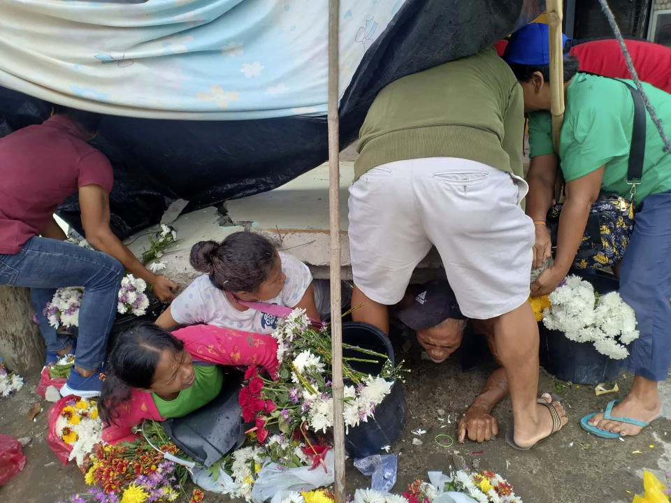Trapped flower vendors are pulled out from a collapsed wall following an earthquake that struck Padada, Davao del Sur province, southern Philippines on Sunday Dec. 15, 2019. A strong quake jolted the southern Philippines on Sunday, causing a three-story building to collapse and prompting people to rush out of shopping malls, houses and other buildings in panic, officials said. (AP Photo/John Angelo Jomao-as)