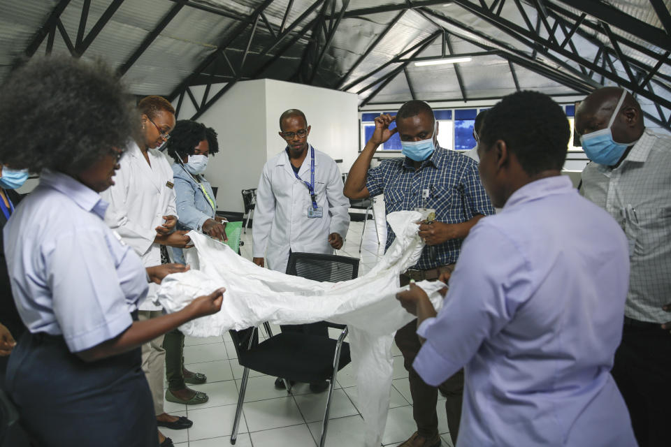 A health inspection officer shows doctors how to use protective equipment before they head to a ward at Mbagathi hospital for patients under quarantine and confirmed cases with the new coronavirus, at Kenyatta National Hospital in Nairobi, Kenya Thursday, April 2, 2020. The new coronavirus causes mild or moderate symptoms for most people, but for some, especially older adults and people with existing health problems, it can cause more severe illness or death. (AP Photo/Brian Inganga)