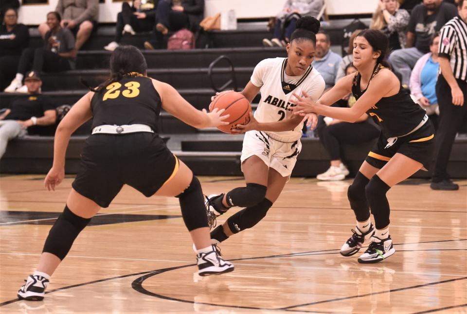 Abilene High's Zikyria Shaw, center, drives between Snyder's Jasmine Hernandez, left, and Jayci Medrano in the second half.