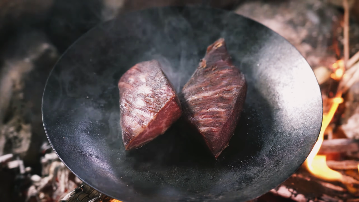 Two slabs of meat cooking in a frying pan. 