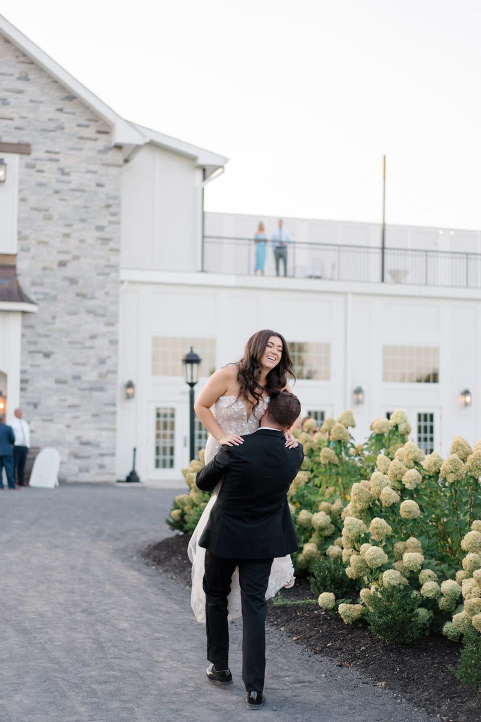 A groom carries his bride on their wedding day.