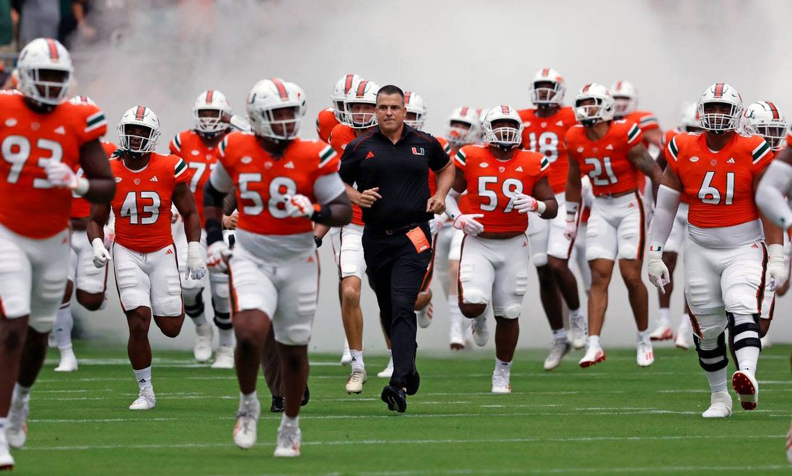 Miami Hurricanes coach Mario Cristobal and the team rush the field before the game against Miami of Ohio Redhawks in Miami Gardens, Florida on Friday, September 1, 2023.