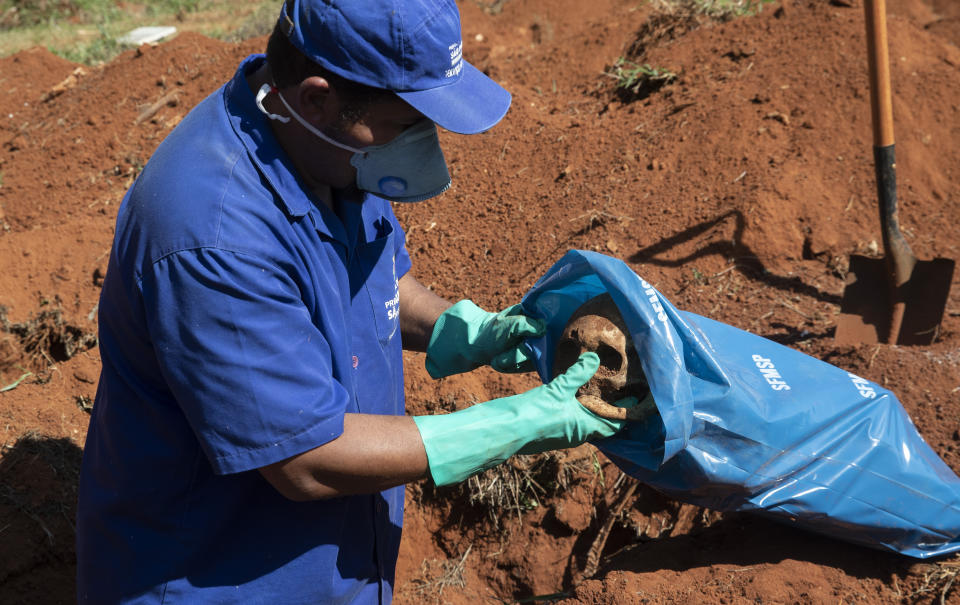 Un operario introduce un cráneo en una bolsa tras exhumar el cuerpo de una persona enterrada hace tres años en el cementerio de Vila Formosa, que no cobra a las familias por las tumbas, en Sao Paulo, Brasil, el 12 de junio de 2020. Los cuerpos sepultados hace al menos tres años, se exhuman y almacenan en bolsas de plástico para dejar sitio a más féretros, una necesidad más acuciante en la pandemia del coronavirus. (AP Foto/Andre Penner)