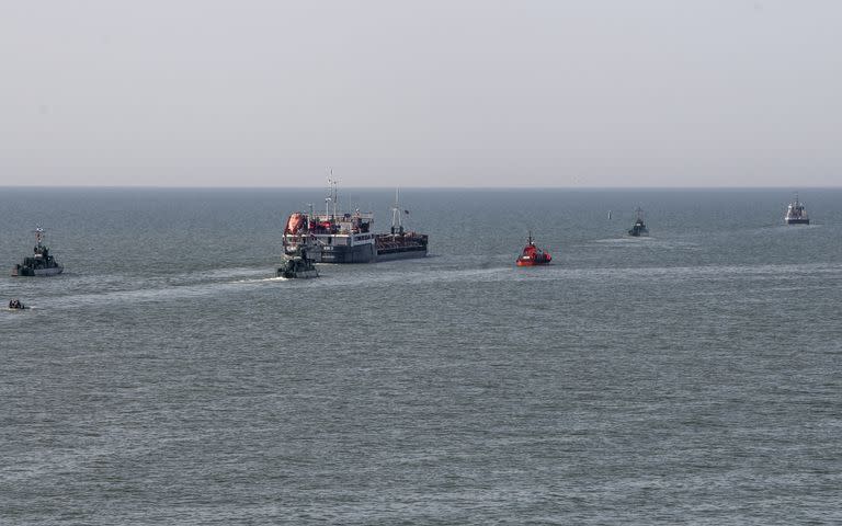 Un barco ruso, al centro, escoltado por botes militares rusos, sale del puerto de Mariúpol, en territorio controlado por la República Popular de Donetsk, en el este de Ucrania, el martes 31 de mayo de 2022. (AP Foto)