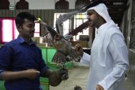 Qatari Ali Alansi, right, looks at a falcon for sale in a shop in Doha, Qatar, Saturday, Nov. 19, 2022. Qatar has become synonymous with soccer since winning the rights to host the FIFA World Cup that opens on Sunday. But another sport is flying high in the historic center of Doha as over a million foreign fans flock to the tiny emirate: Falconry. (AP Photo/Jon Gambrell)