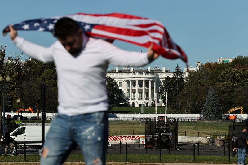 A tourist with a U.S. flag poses for photographs with his friends near the White House the day after Election Day in Washington