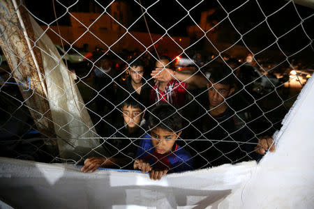 Palestinians watch through a fence the funeral of Palestinian woman Zena Al Omor, whom hospital officials said was killed by fragments of an Israeli tank shell, in the southern Gaza Strip May 5, 2016. REUTERS/Ibraheem Abu Mustafa