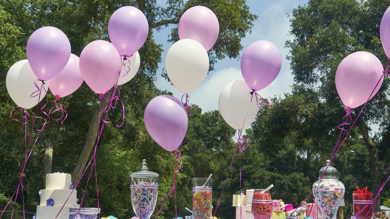 balloons and candy laid out on a table outside for a baby shower