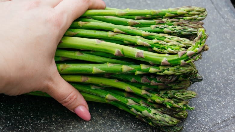 A hand holding a bunch of asparagus