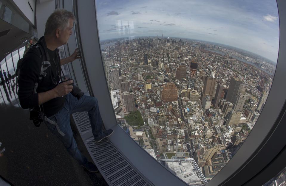 A news photographer looks out the window at the Manhattan skyline from the One World Observatory observation deck on the 100th floor of the One World Trade center tower in New York