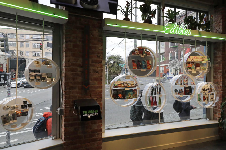 In this photo taken March 24, 2020, customers line up on the sidewalk outside The Reef Capitol Hill, a marijuana store in Seattle and observe social distancing chalk marks on the sidewalk as they wait to get into the store, which was limiting the number of people inside at one time to help slow the spread of the new coronavirus. Earlier in the week, Washington Gov. Jay Inslee ordered nonessential businesses to close and the state's more than 7 million residents to stay home in order to slow the spread of the new coronavirus. In Washington and several other states where marijuana is legal, pot shops and workers in the market's supply chain were deemed essential and allowed to remain open. (AP Photo/Ted S. Warren)