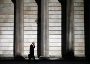 A man speaks on his phone on a sunny morning as he walks past the columns of the Bank of England in the City of London, May 19, 2014. REUTERS/Andrew Winning