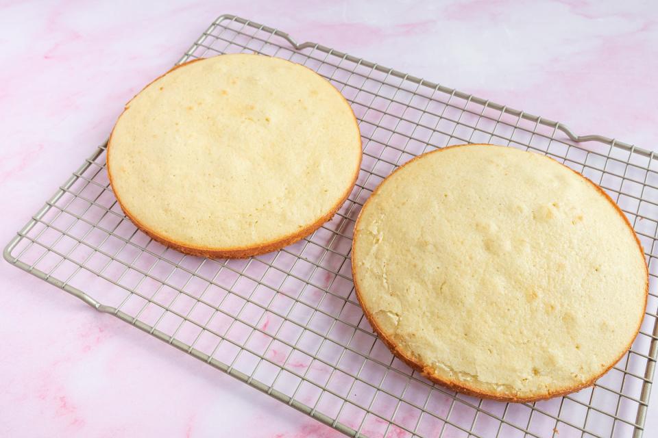 two round yellow cakes on a wire metal cooling rack