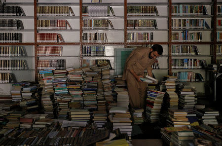 A librarian selects books which are being catalogued in the library at the Al-Nadwa Madrassa in Murree, Pakistan, October 24, 2017. REUTERS/Caren Firouz