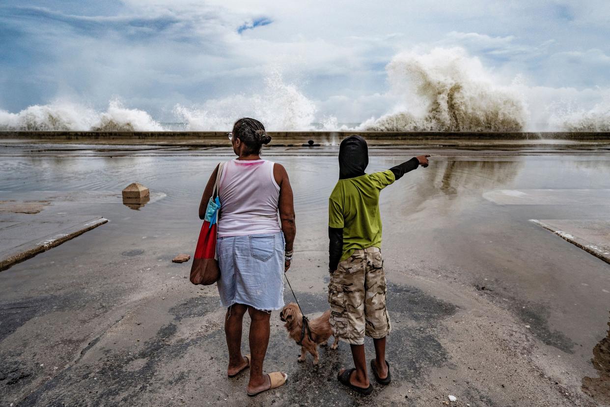 A woman and a boy observe the waves hitting the Malecon in Havana, Cuba on Sept. 28, 2022, after the passage of Hurricane Ian.