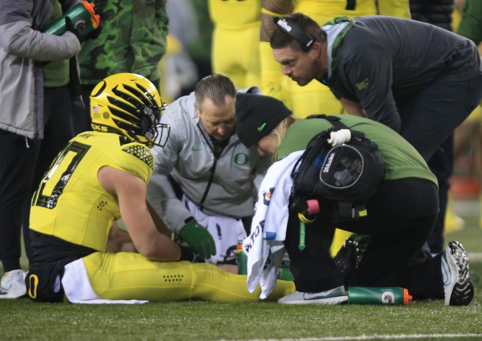 Oregon quarterback Bo Nix, left, sits in the turf after being injured on a fourth quarter play against the Washington Huskies Saturday, Nov. 12, 2022, at Autzen Stadium in Eugene, Ore.