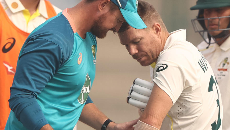 David Warner has his arm looked at by an Australian trainer.