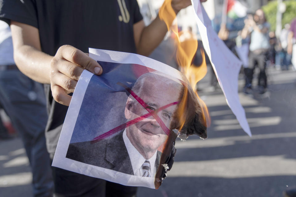 Palestinian activists burn defaced pictures of U.S. President Joe Biden while protesting his upcoming visit to the Palestinian territories, in the West Bank city of Ramallah, Thursday, July 14, 2022. (AP Photo/Nasser Nasser)