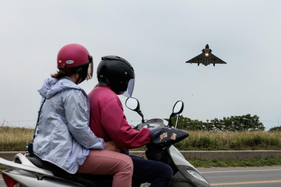 Two people ride a motorcycle as a Taiwanese Air Force Mirage 2000 fighter jet approaches for landing at an air force base in Hsinchu in northern Taiwan on 23 May 2024 (AFP via Getty Images)