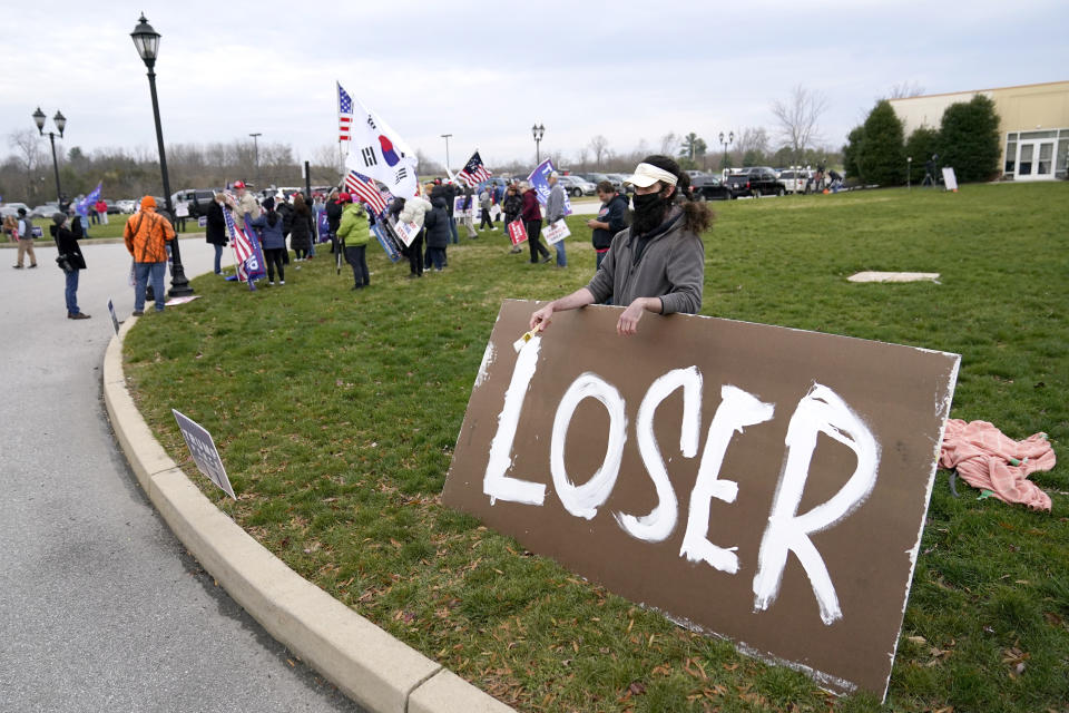 Supporters of President Donald Trump, left, gather as a counter protester holds a sign outside of the Wyndham Hotel where the Pennsylvania State Senate Majority Policy Committee is scheduled to meet, Wednesday, Nov. 25, 2020, in Gettysburg, Pa. (AP Photo/Julio Cortez)