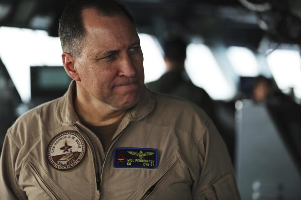 In this Tuesday, March 21, 2017 photograph, Capt. Will Pennington, the commanding officer of the USS George H.W. Bush, greets journalists as the ship travels through the Persian Gulf. The arrival of the nuclear-powered aircraft carrier to the Persian Gulf marks the first such deployment under new U.S. President Donald Trump. (AP Photo/Jon Gambrell)